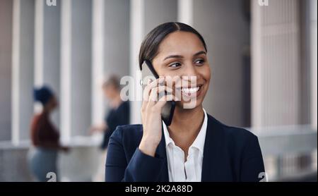 New clients are just a call away. Shot of a young businesswoman using a smartphone against a city background. Stock Photo