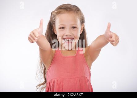 I give you a thumbs up. Studio portrait of a cute young girl giving a thumbs-up to the camera. Stock Photo