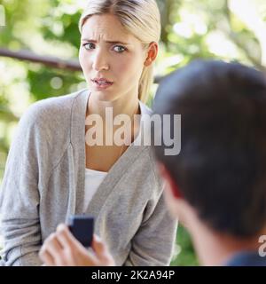 Are you kidding me. Shot of a beautiful young woman looking uncertain as her boyfriend is proposing. Stock Photo