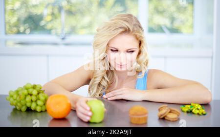 Temptation - Eat right and stay healthy. Pretty young woman being tempted to eat unhealthy food. Stock Photo