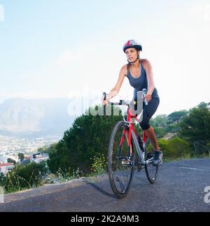 Enjoying the view from the top. Shot of a lone female rider cycling on a rural road with copy space. Stock Photo