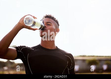 Get hydrated, were going in for the second half. Shot of a young man drinking water after playing a game of rugby. Stock Photo