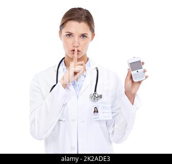 Doctor-client privelage. Portrait of an attractive young doctor telling you to be quiet while holding a cellphone. Stock Photo