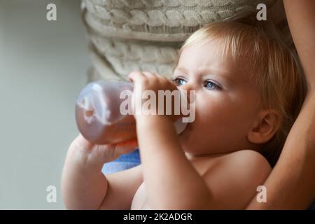 Safe in his mothers arms. A baby boy drinking from his bottle while being held by his mother. Stock Photo