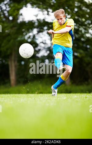 Bending the ball towards a goal. Shot of a soccer player kicking the ball with gusto. Stock Photo