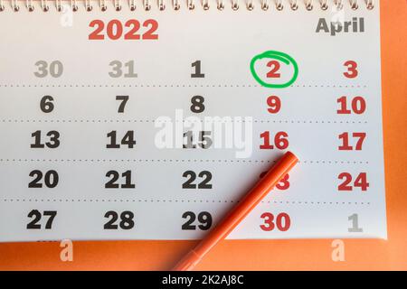 International Children's Book Day, wall-mounted paper calendar with a highlighted date of April 02, 2022 and an orange marker, top view Stock Photo