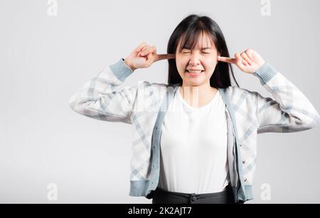 Woman bad mood pain her closed ears with finger and close eyes Stock Photo