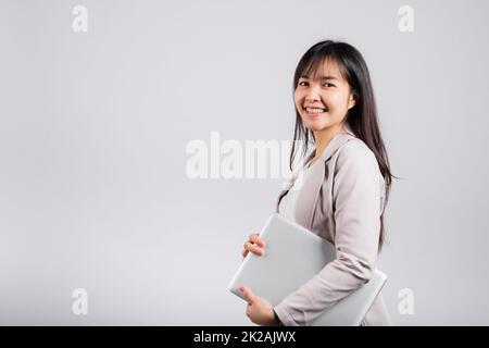 Side view woman smiling confident smiling holding closed laptop Stock Photo