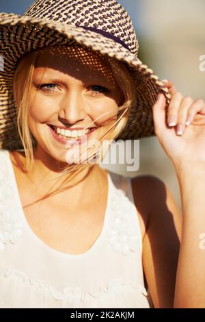 Enjoying a day in the sun. A beautiful young woman wearing a straw hat. Stock Photo