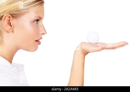 This is my lucky ball. Profile view of a young female golfer holding a golf ball in her palm isolated on white. Stock Photo