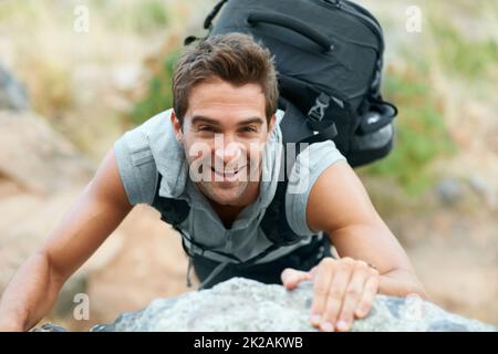 Climb every mountain. Young mountain climber smiling up at the camera. Stock Photo