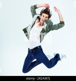 Having fun and going crazy. Portrait of a happy young man jumping up into the air. Stock Photo