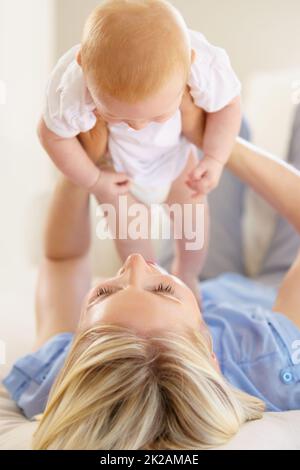 Mom and daughter bonding together. An adorable baby girl being lifted into the air by her mother. Stock Photo