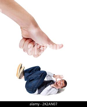 Stuck under some elses thumb. A fearful young man lying on the ground with a giant thumb looking to squash him. Stock Photo