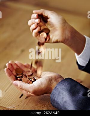 Playing with money. A closeup of hands pouring coins from one into the other. Stock Photo