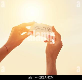 Success is in your hands. Cropped shot of an unidentifiable woman holding up a note against the summer sky. Stock Photo
