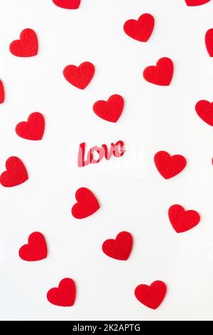 The background which consists of red hearts, the inscription love in the middle of the hearts. Vertical photo. Love concept, greeting card for valentine's day. Stock Photo