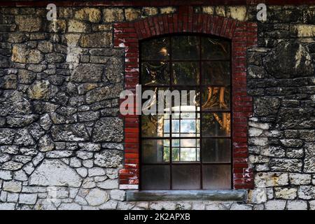 An old translucent window in a vacant building with stone wall Stock Photo