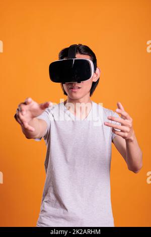 Man wearing vr headset playing virtual reality games in cyber space, enjoying simulation experience, exploring metaverse. Cyberspace entertainment, leisure activity, modern technology Stock Photo