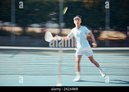Asian tennis professional training with a racket and playing a game on court. Fit athlete running during a match and play competitive sport workout Stock Photo