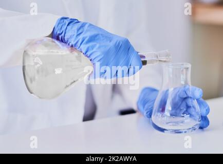 Discovering chemical reactions. Cropped shot of a scientist mixing chemicals in beakers while standing in a laboratory. Stock Photo