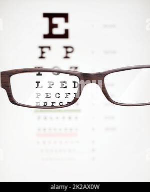 Zoom in on life. A cropped shot of eyeglasses in front of a snellen chart. Stock Photo