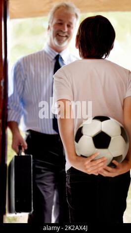Guess what were doing after work dad. Father coming home to his son waiting to practice soccer. Stock Photo
