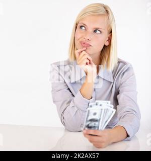 Deciding what to do with her money. A pretty young woman wondering what to do with her cash. Stock Photo