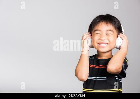 Little cute kid boy 5-6 years old listen music wear wireless headphones in studio shot isolated Stock Photo