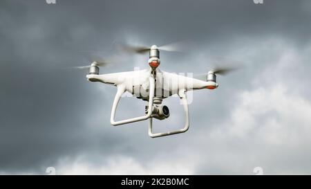 Drone DJI Phantom 4 in flight. Dron against the cloudy sky. The flight of the drone before a thunderstorm. The flight of the copter in the sky. Stock Photo