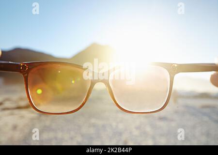 Looking at the bright side of life. POV shot of a person at the beach looking at the view through their sunglasses. Stock Photo