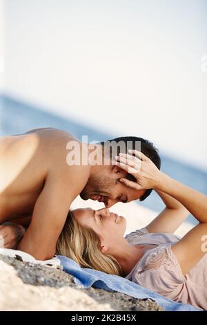 The perfect beach romance. Shot of an affectionate young couple enjoying a romantic day at the beach. Stock Photo