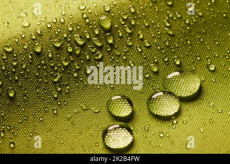 Top view green background with closeup round drops of water on water impregnated textile with wet and textured surface in room Stock Photo