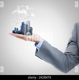 The whole city in the palm of your hand. Cropped studio shot of a businessmans arm holding a miniature city. Stock Photo