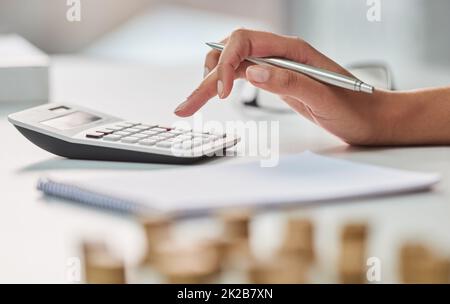 Making sure her rainy days are covered. Cropped shot of an unrecognizable businesswoman working out her finances with a calculator and a notepad in her office. Stock Photo