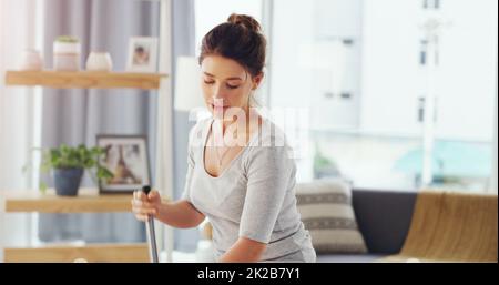 I clean because I feel happier in a clean house. Cropped shot of a young woman mopping the floor in her living room. Stock Photo