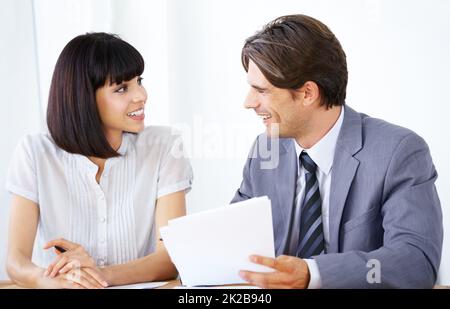 Putting their minds together to succeed. Two young executives enjoying a conversation in the office together. Stock Photo