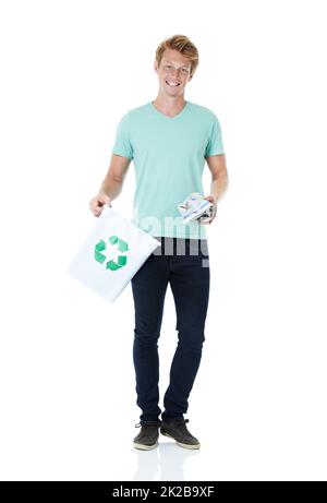 Getting in the right habit. A handsome young red-headed man ready to throw away a piece of paper in the recycling bin - portrait. Stock Photo