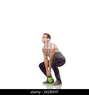 Crouching with his kettlebell. A handsome young man working out with a kettlebell while isolated on a white background. Stock Photo