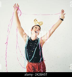 Never miss out on a chance to celebrate in life. Shot of an attractive and cheerful young woman celebrating with confetti falling around her against a grey background. Stock Photo