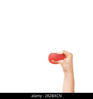 Crushing out all that stress. Cropped view of a womans hand squeezing a stress ball against a white background. Stock Photo