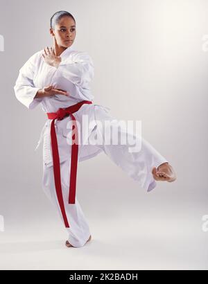 Shes got a solid kick. Shot of a young woman doing karate. Stock Photo