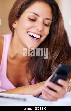 Pretty woman reading a funny text message. Pretty young woman taking a break from study and reading a funny text message. Stock Photo