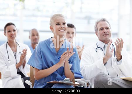 Celebrating breakthroughs in healthcare. Doctors and nurses applauding their lecturer. Stock Photo