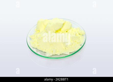 Sulfur Powder in Chemical Watch Glass. Closeup chemical ingredient on white laboratory table. Stock Photo