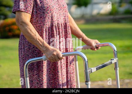 Asian senior or elderly old lady woman use walker with strong health while walking at park in happy fresh holiday. Stock Photo