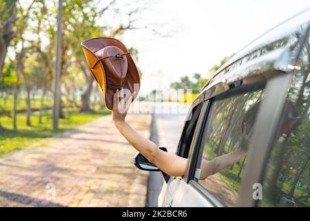 Happy enjoy and freedom in traveling trip with raised hand and holding cowboy hat outside of window car in summer vacation holiday Stock Photo