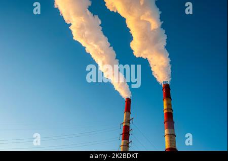 white smoke is coming out of the pipes in the blue sky Stock Photo