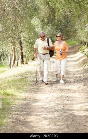 Staying active while enjoying nature. A senior couple walking together along a forest trail. Stock Photo