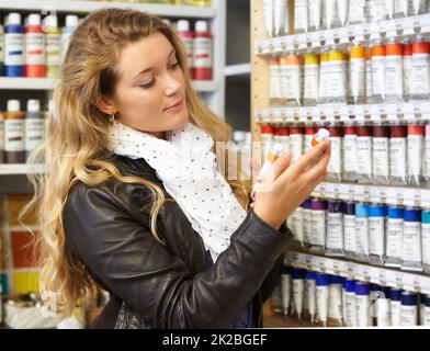 She has the complete range to choose from. Shot of a young female artist shopping for paint in an art store. Stock Photo